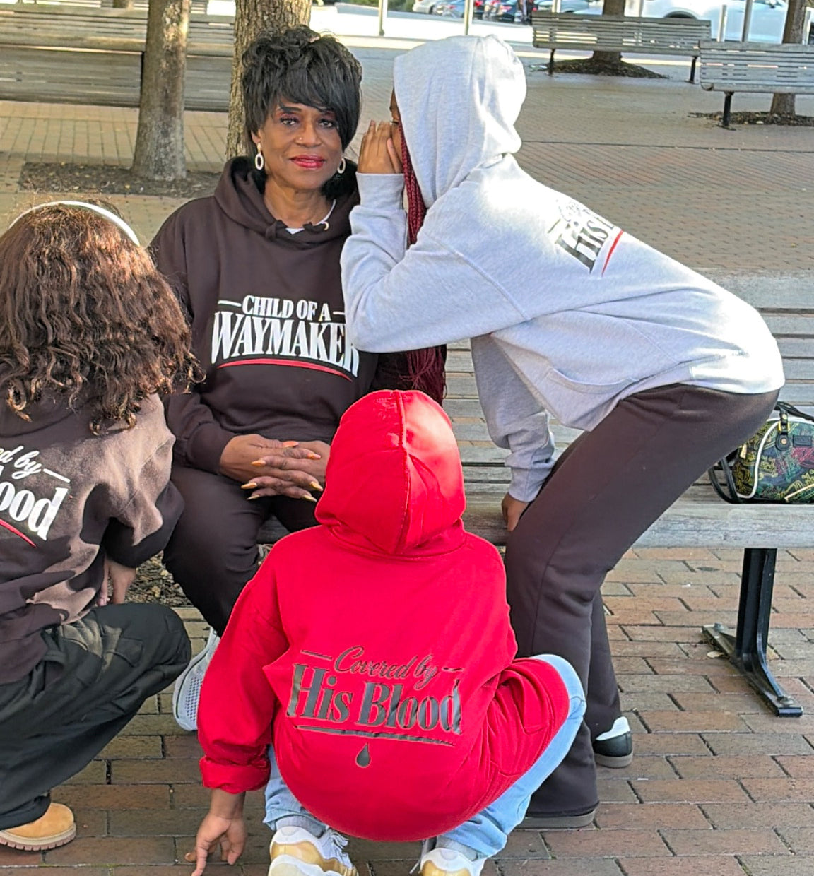 Kids whispering a secret to Grandma wearing WAYMAKER hoodies